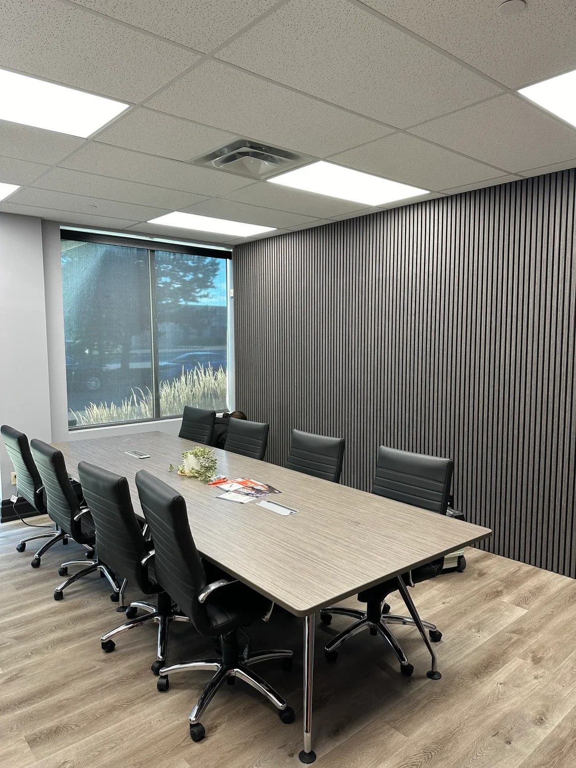 Office boardroom with a full-length grey slat acoustic wall running behind the conference table.